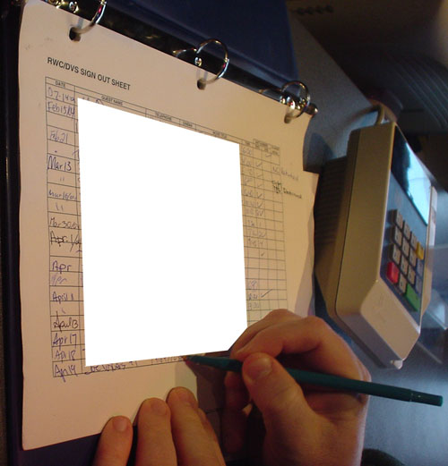 Binder holds page reading RWC/DVS SIGN OUT SHEET. Hand holds pen and writes on the page. Photo has a large segment deleted from the sheet