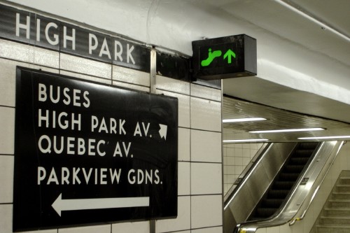 White letters on a black sign read BUSES HIGH PARK AV. QUEBEC AV. and other messages