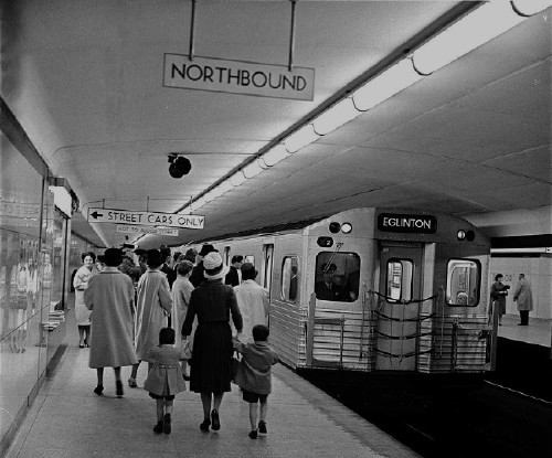 Subway train in with destination EGLINTON sits in glossy-tiled station. Signs in black type on white read NORTHBOUND, ← STREET CARS ONLY, NOT TO BLOOR STREET
