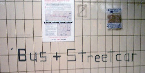 Duct tape on wall forms the words Bus + Streetcar